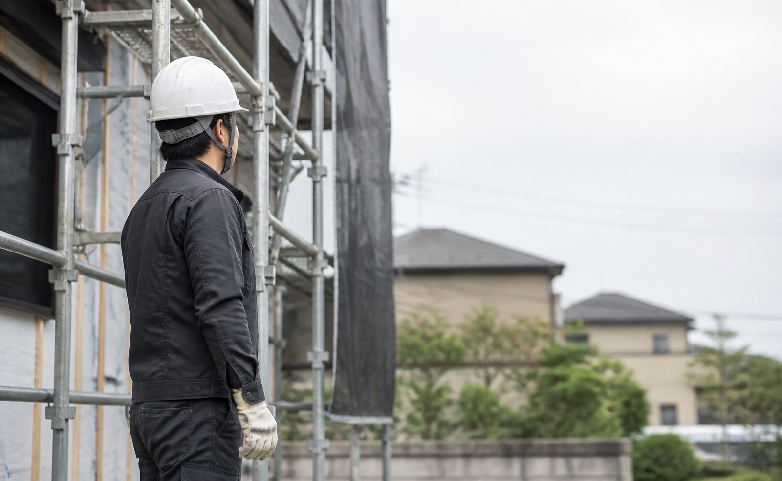 足場のそばで現場を確認する作業員